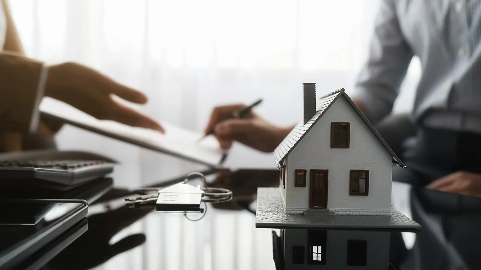 Homeowner reviewing an insurance claim with a model house and keys on the desk