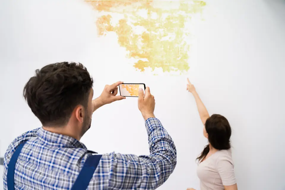 Water damage inspection of a stained wall with the homeowner